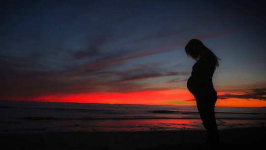 A Fight for Life and a Love Story: Saturn and Uranus a pregnant woman in silhouette with the sunrise in the background